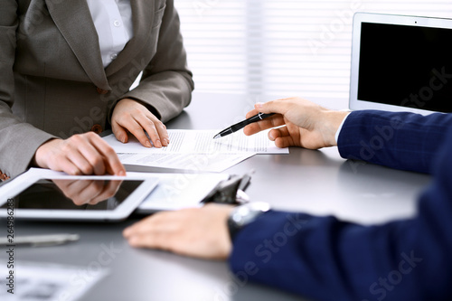 Business people and lawyer discussing contract papers sitting at the table, hands close-up. Teamwork or group operations concept photo