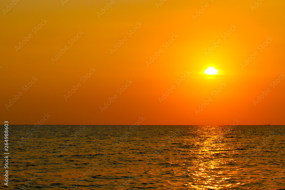 Bright sunset with large yellow sun above the sea surface. Last colors the day. Summer vacation and nature travel is adventure concept background.