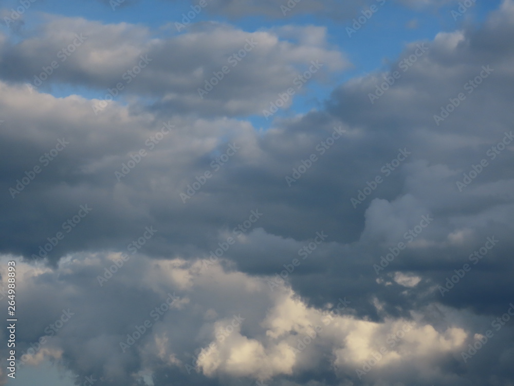 Soft white and grey stratocumulus clouds on a blue sky on a summer day before light rain