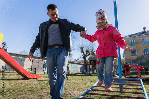 Father helps daughter to keep balance on the stairs