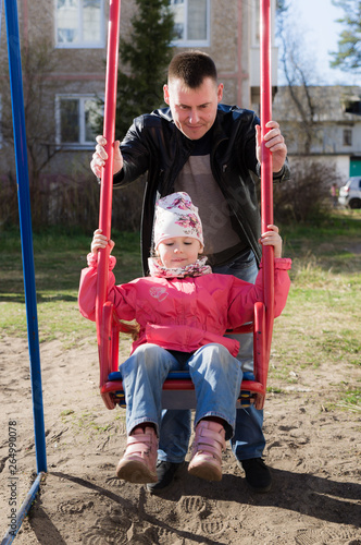 Father swinging daughter on a swing in the city