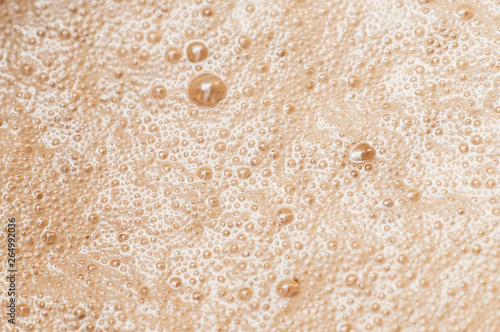 foam on coffee with milk close-up in macro of air bubbles after chipping milk or cream with a glare from lighting