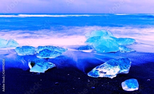 View of the icebergs flowed from the Jokulsarlon Glacier Lagoon to beachside in Iceland at twilight in winter.