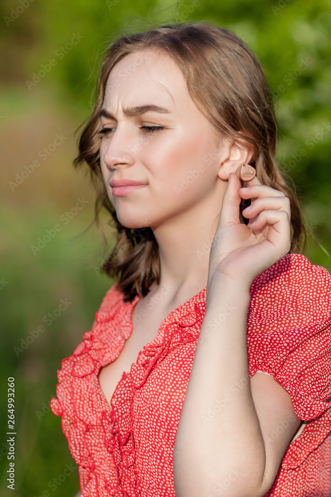 Close-up Of Female Hands Putting Hearing Aid In Ear. Modern digital in the ear hearing aid for deafness and the hard of hearing patients