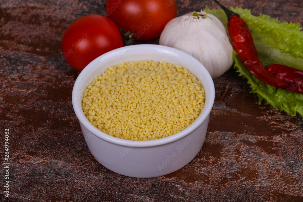 Raw couscous in the bowl served salad leaves, tomato and pepper Raw couscous in the bowl served salad leaves, tomato and pepper