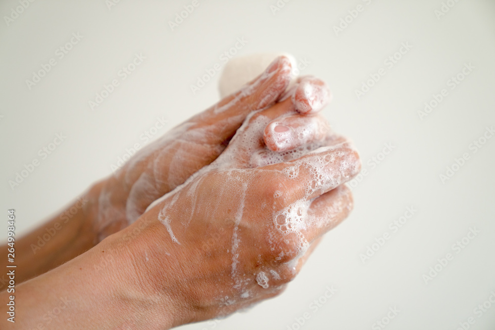 close up of woman washing her hands with a bar of soap and soapy suds close up of woman washing her hands with a bar of soap and soapy suds
