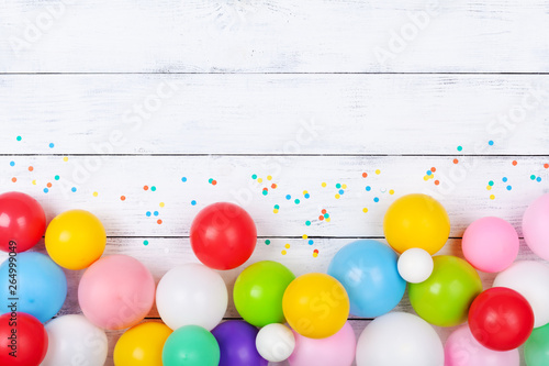 Colorful balloons and confetti on white table top view. Festive or party background. Flat lay. Birthday greeting card.