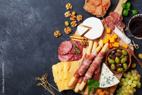 Italian appetizers or antipasto set with gourmet food on black kitchen table top view. Mixed delicatessen of cheese and meat snacks with red wine. photo