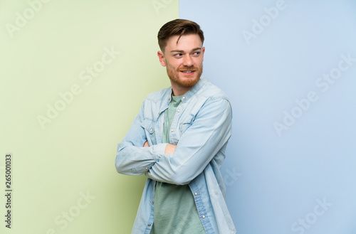 Redhead man over colorful background with arms crossed and happy