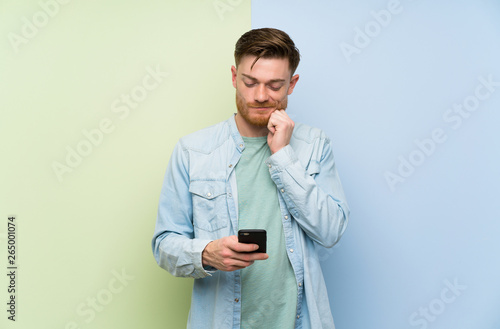 Redhead man over colorful background thinking and sending a message