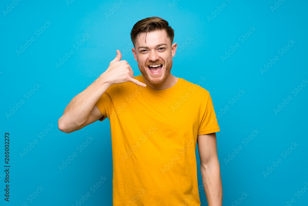 Redhead man over blue wall making phone gesture. Call me back sign Redhead man over blue wall making phone gesture. Call me back sign