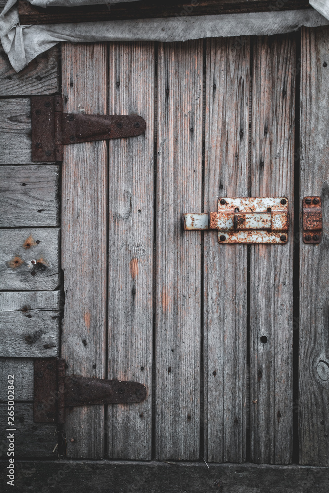 Old wooden door and rusty deadbolt in a small barn Old wooden door and rusty deadbolt in a small barn