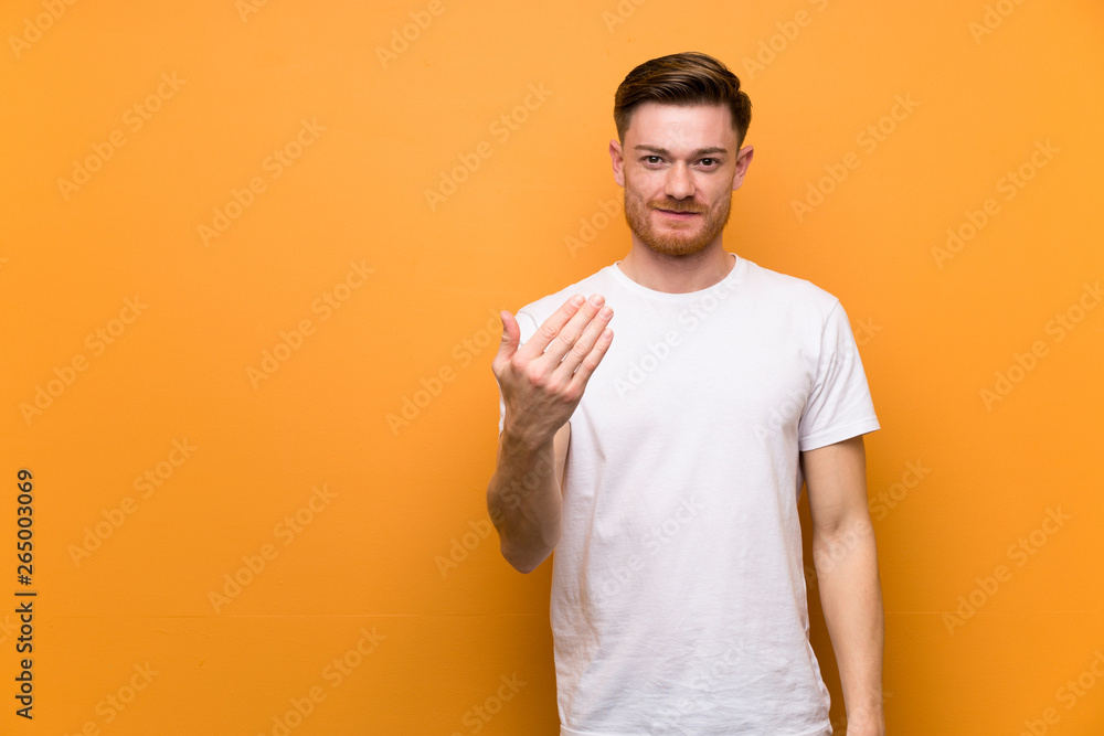 Redhead man over brown wall inviting to come with hand. Happy that you came Redhead man over brown wall inviting to come with hand. Happy that you came