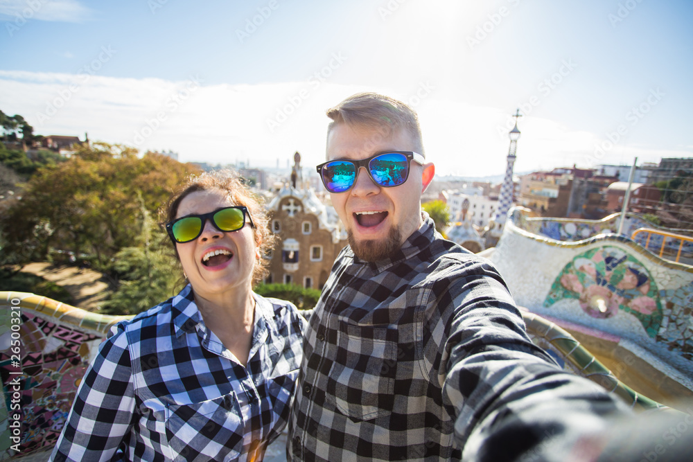 Funny young couple looking at camera taking photo with smart phone smiling in Park Guell, Barcelona, Spain. Funny young couple looking at camera taking photo with smart phone smiling in Park Guell, Barcelona, Spain.