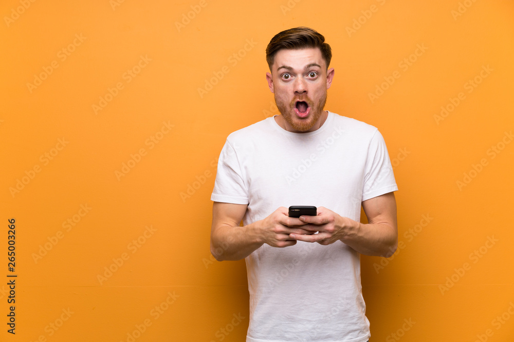 Redhead man over brown wall surprised and sending a message Redhead man over brown wall surprised and sending a message