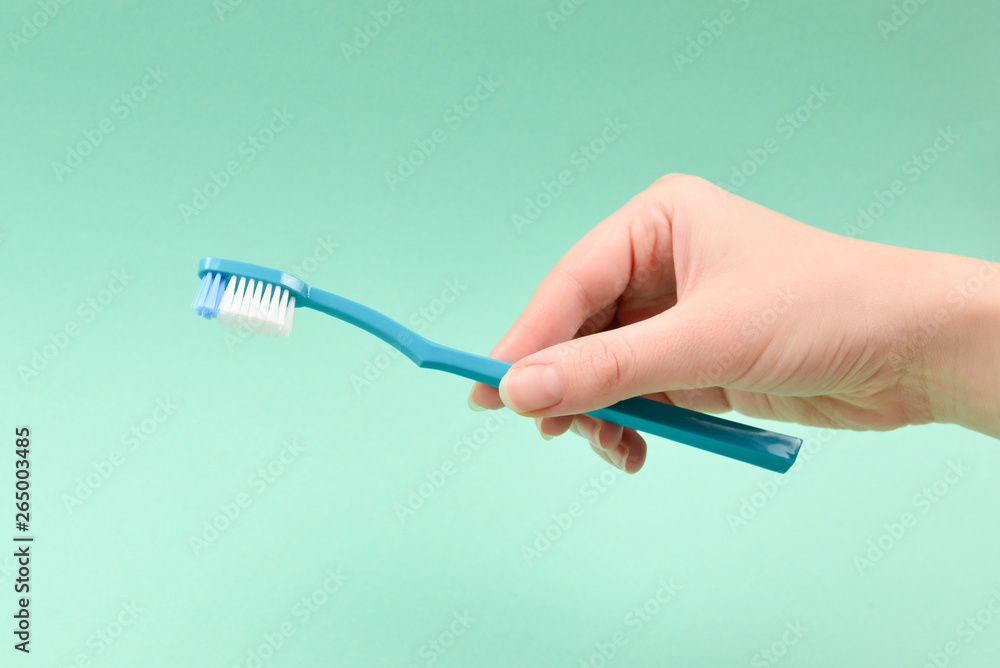 The woman holds toothbrushes in her hand on a green background. The woman holds toothbrushes in her hand on a green background.