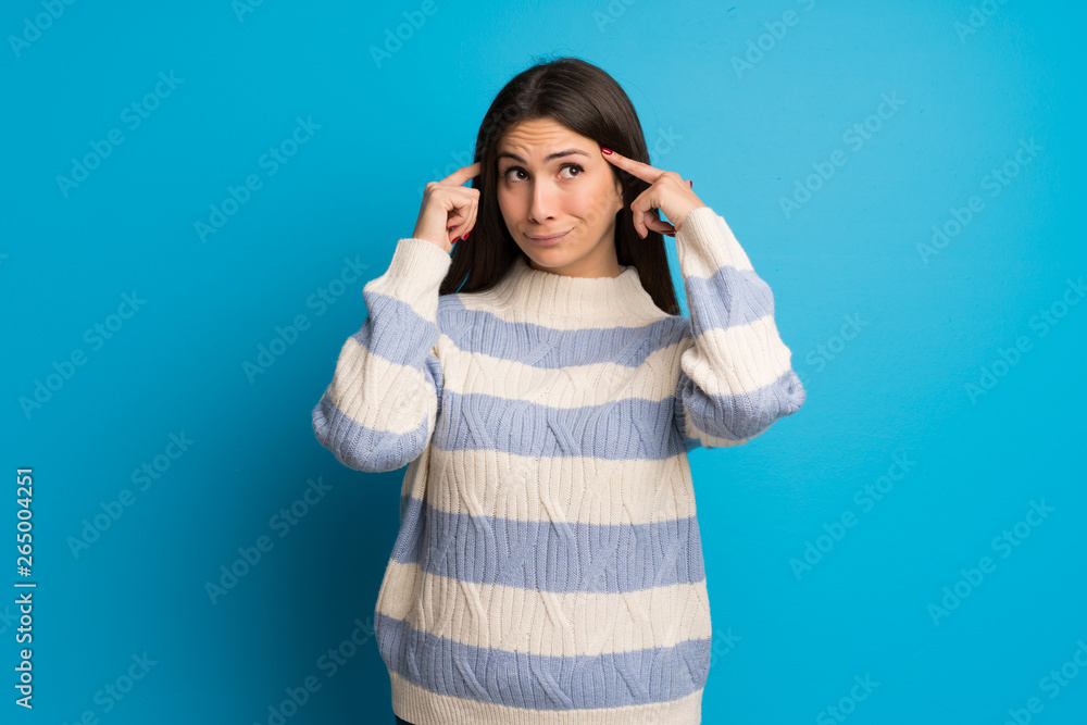 Young woman over blue wall having doubts and thinking Young woman over blue wall having doubts and thinking