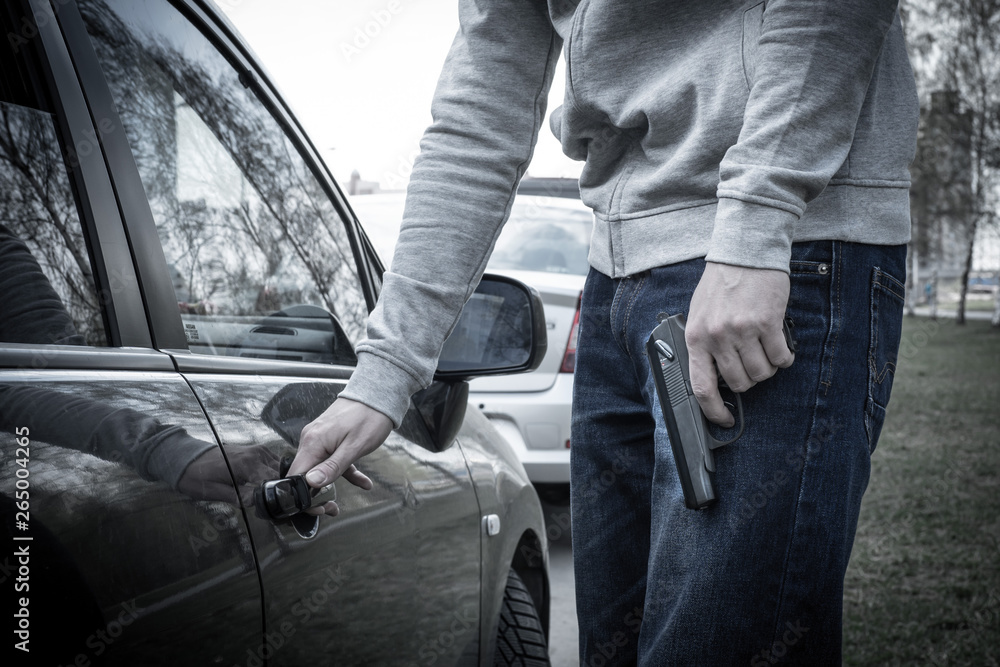 man opens the car door with a gun in his hand. the criminal steals the car. criminal district of the city man opens the car door with a gun in his hand. the criminal steals the car. criminal district of the city