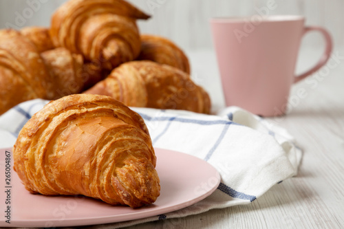 Fresh croissant on a pink plate, side view. Close-up.