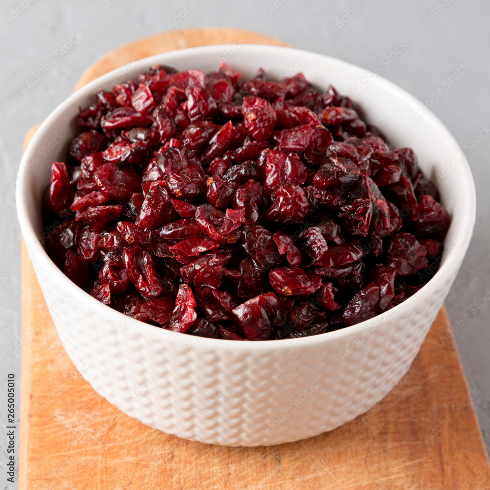 Dried cranberries in a bowl over gray background, side view. Close-up. Dried cranberries in a bowl over gray background, side view. Close-up.