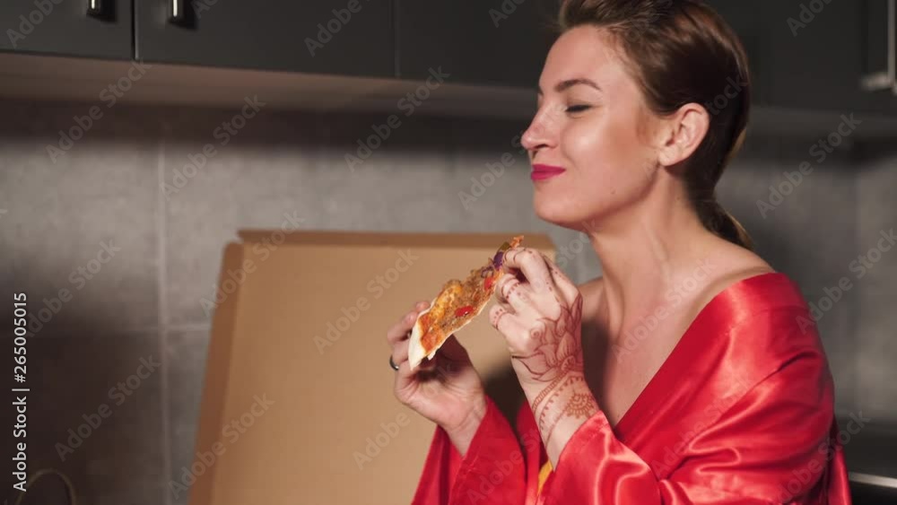 Two girlfriends women eating pizza and enjoying an evening party chat before going out - One wearing blue morning gown, the other red robe dress - Laughing and smiling Two girlfriends women eating pizza and enjoying an evening party chat before going out - One wearing blue morning gown, the other red robe dress - Laughing and smiling