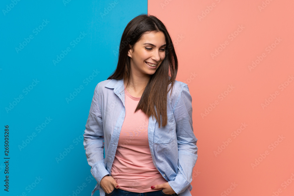 Young woman over pink and blue wall happy and smiling Young woman over pink and blue wall happy and smiling
