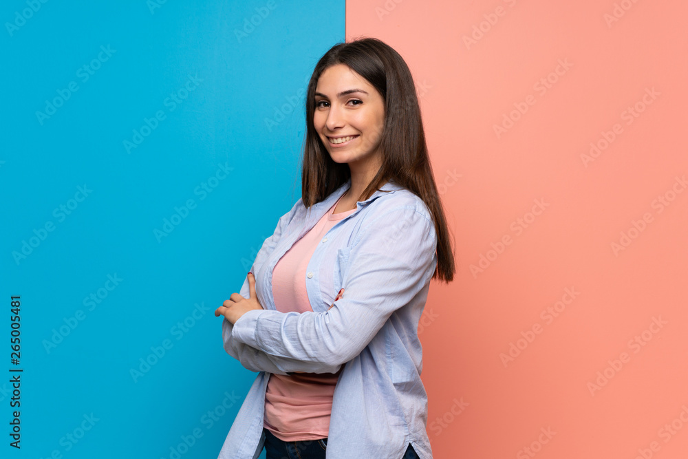 Young woman over pink and blue wall with arms crossed Young woman over pink and blue wall with arms crossed