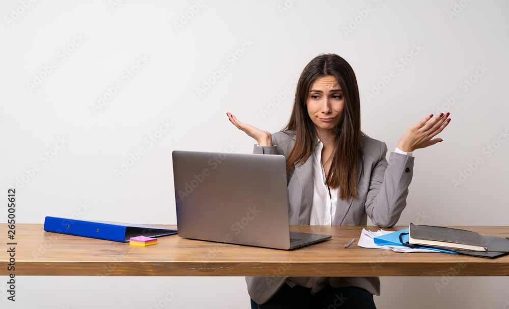 Business woman in a office having doubts while raising hands Business woman in a office having doubts while raising hands