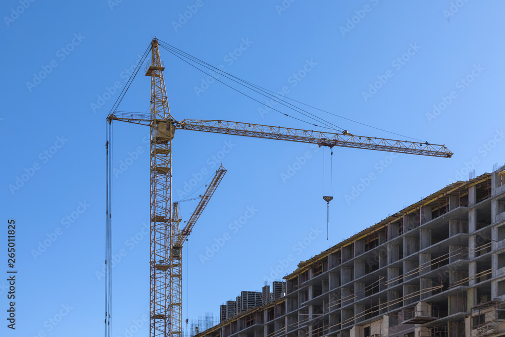 The building of the house. The crane and the new brick building in the clear sunny day on the background of blue sky The building of the house. The crane and the new brick building in the clear sunny day on the background of blue sky