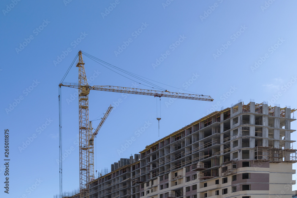 The building of the house. The crane and the new brick building in the clear sunny day on the background of blue sky The building of the house. The crane and the new brick building in the clear sunny day on the background of blue sky
