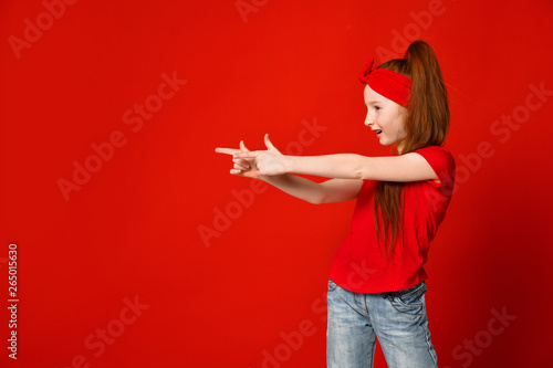 Little red-haired girl in a red t-shirt makes a gesture with her hands to takes aim © FAB.1