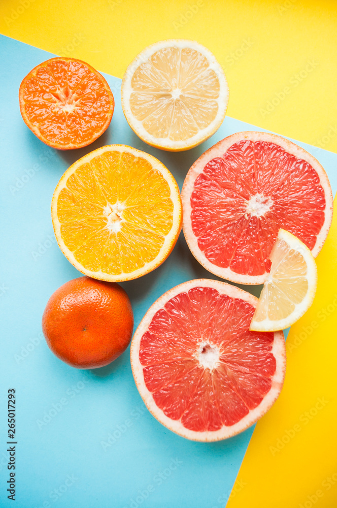 Flat lay of cut ripe juicy grapefruit, lemon and orange on yellow and blue background. Citrus pattern. Flat lay of cut ripe juicy grapefruit, lemon and orange on yellow and blue background. Citrus pattern.