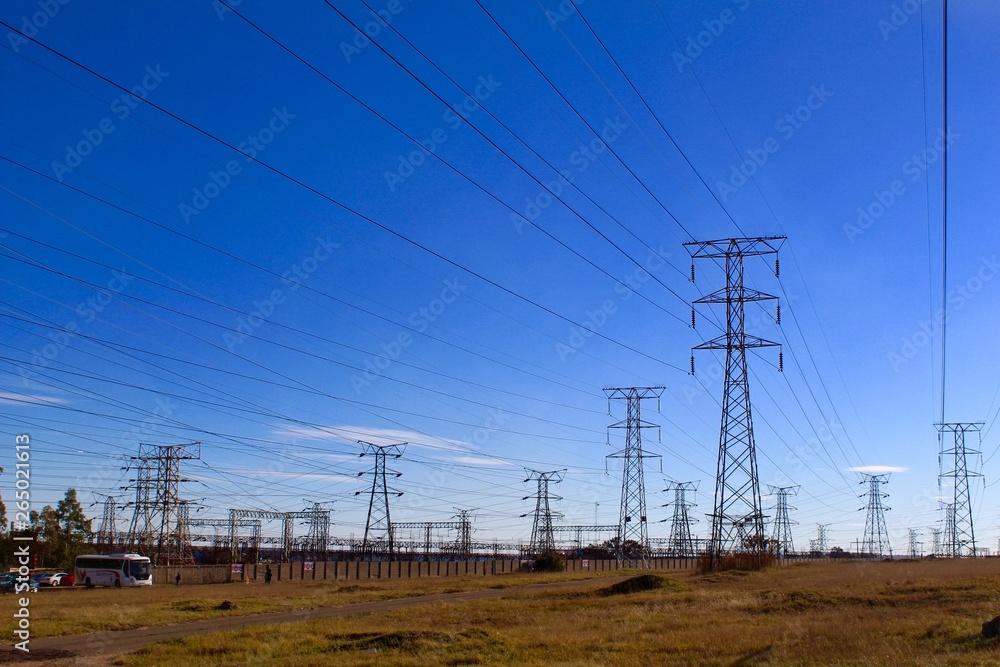 Electricity pylons against blue sky on rough ground Electricity pylons against blue sky on rough ground