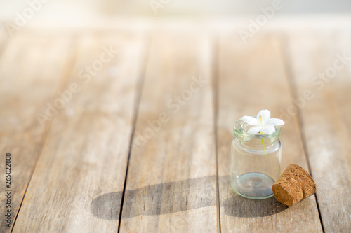Glass bottles have small flowers on the wooden floor.