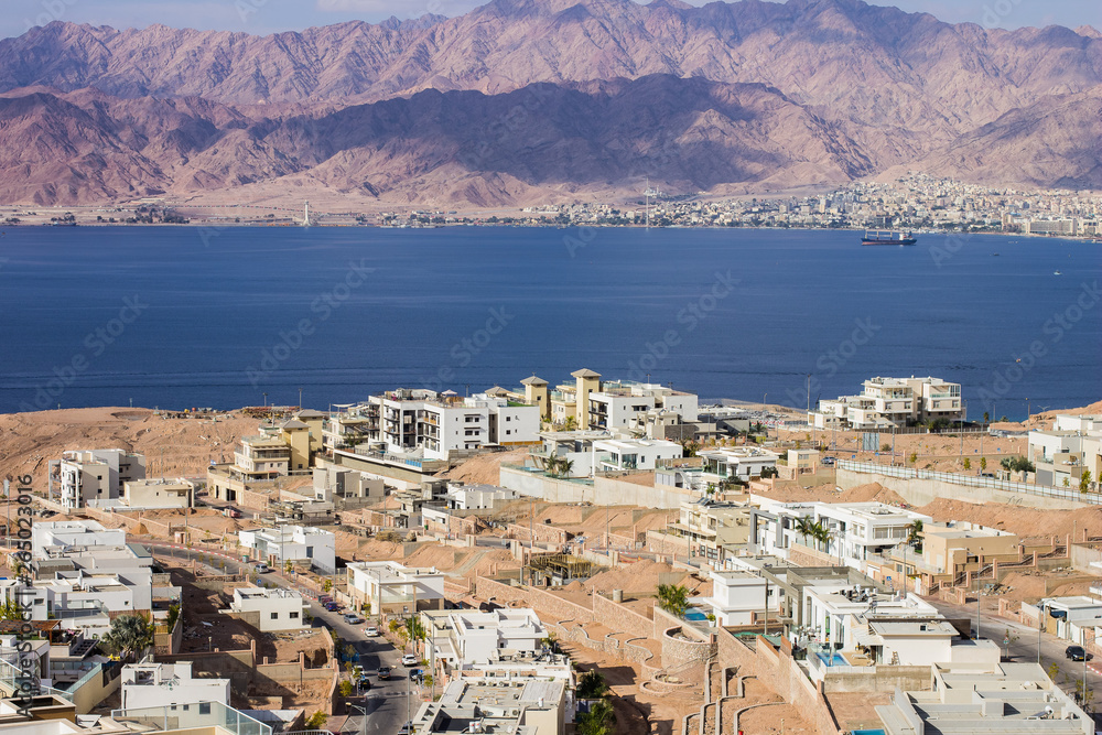 Jewish Israeli city Eilat aerial photography from above with view on a buildings on Red sea Gulf of Aqaba water surface and opposite Jordanian waterfront, Middle East place for summer vacation  