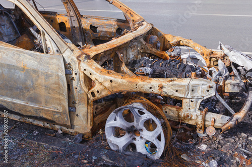 Fotografía burned down car standing in the middle of the carriageway, in a city that cannot be restored