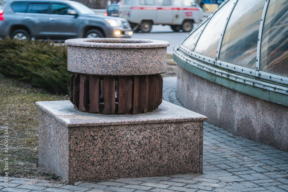Naklejka premium Decorative design of ventilation. Metal grill on a granite ventilation kiosk. Empty flower bed near the street.