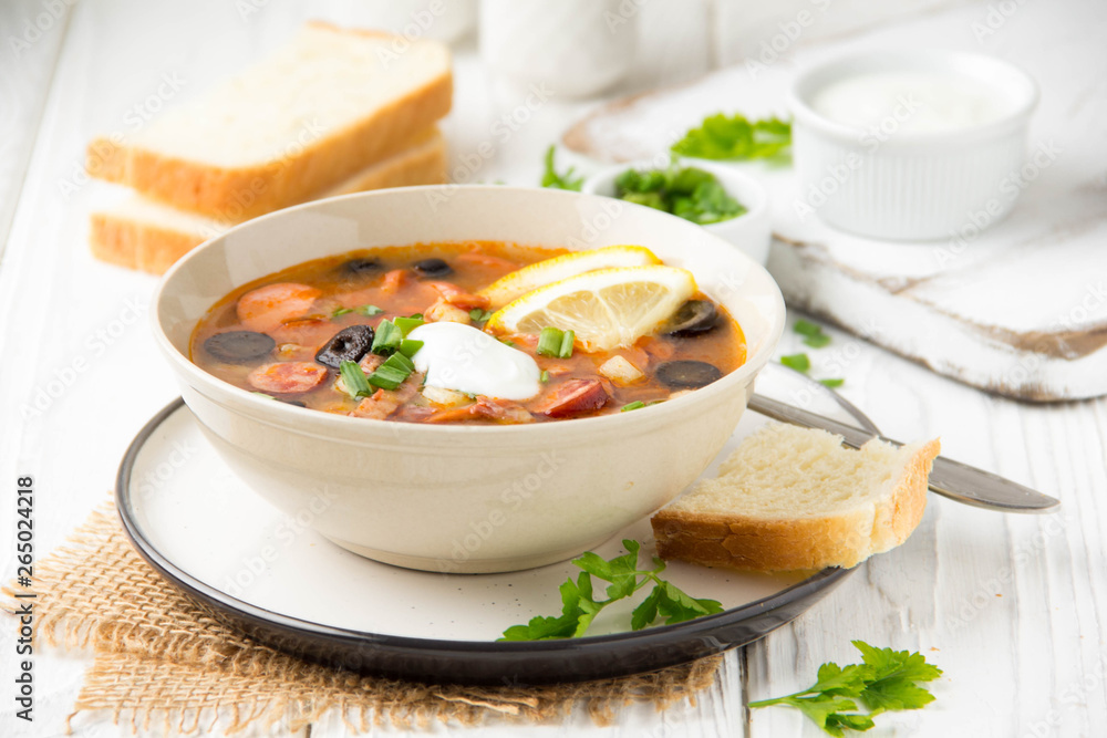 Traditional Russian soup Solyanka with beef, chicken, sausage, lemon, olives and pickled cucumber. Delicious hot lunch, homemade food Traditional Russian soup Solyanka with beef, chicken, sausage, lemon, olives and pickled cucumber. Delicious hot lunch, homemade food