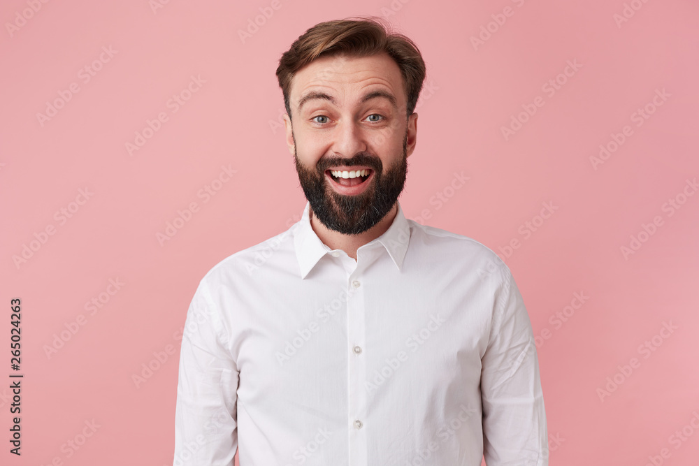 Φωτογραφία Portrait of happy young handsome bearded man, wearing a white shirt, heard the good news
