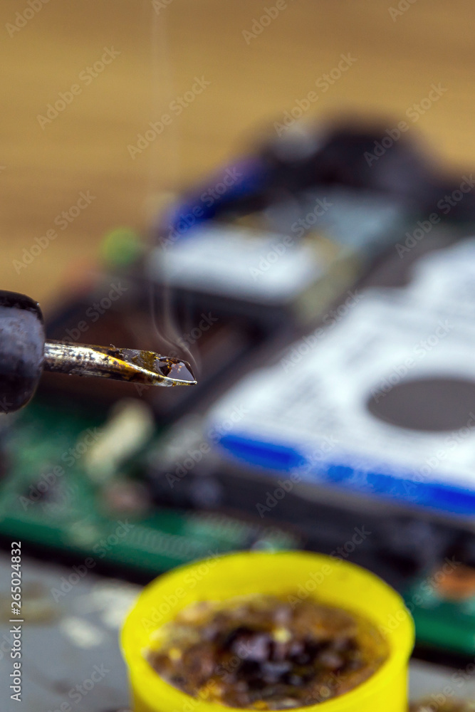 smoke from boiling rosin on a heated soldering iron, disassembled electronic apparatus in the background. selective focus, close smoke from boiling rosin on a heated soldering iron, disassembled electronic apparatus in the background. selective focus, close