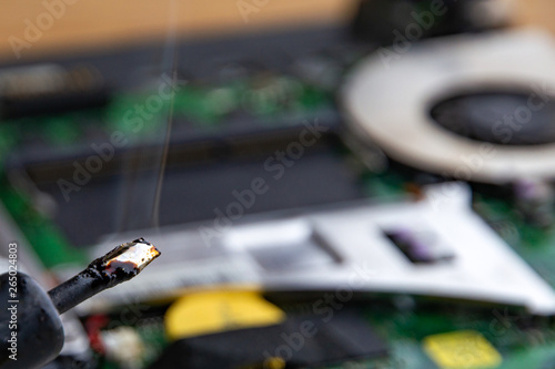 smoke from boiling rosin on a heated soldering iron, disassembled electronic apparatus in the background. selective focus, close