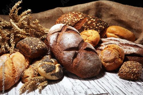 Assortment of baked bread and bread rolls on rustic white bakery table background