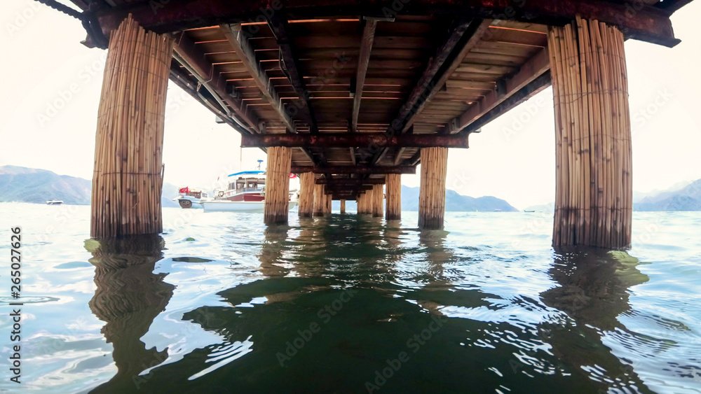 View from under the wooden pier on calm sea waves
