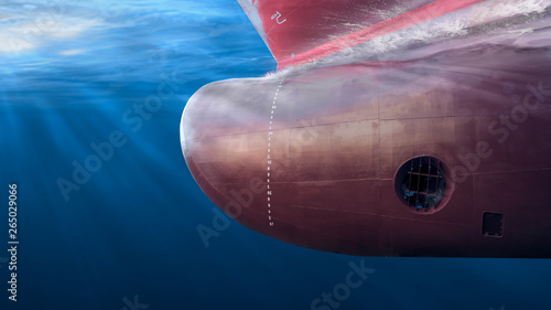 Big cargo ship sailing in the sea to International Shipping container terminal. Close up image detail ships bow, underwater view with sun rays.