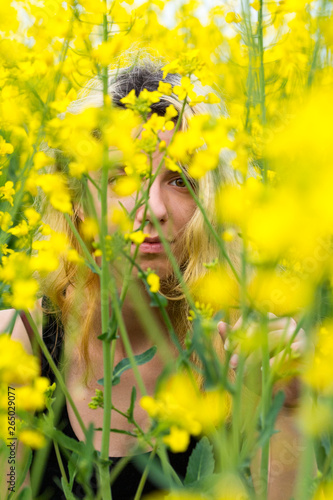 A blonde girl hiding in a canola field