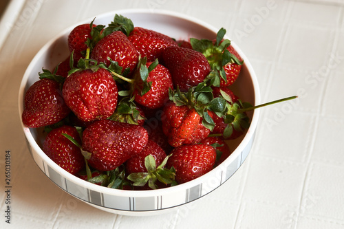 Red fresh strawberry in a bowl on white background with copy space