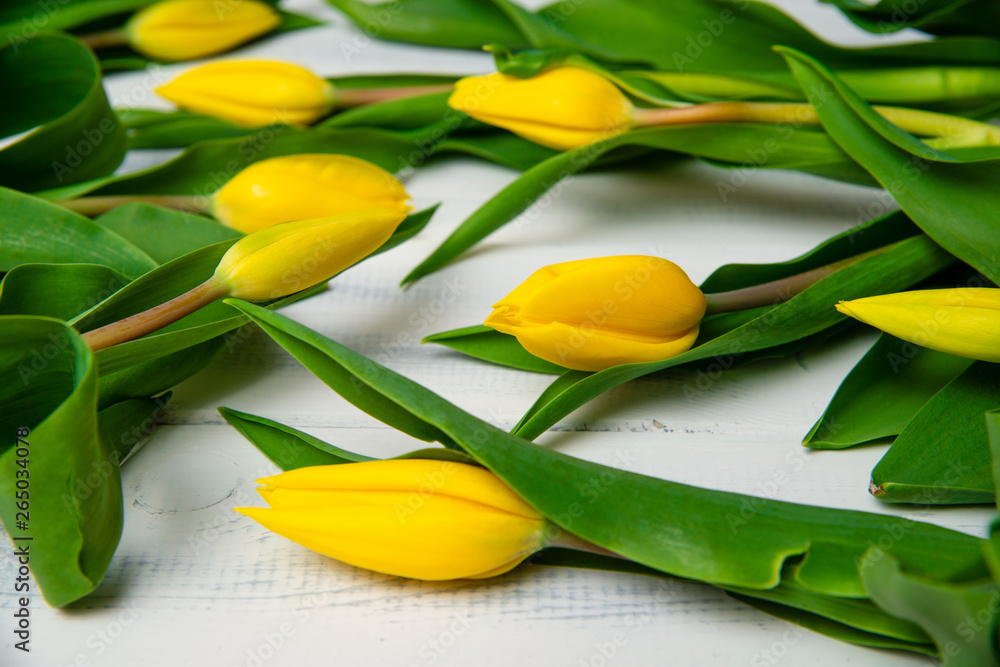Obraz premium Top view of yellow tulips on a wooden table. The concept of handing flowers to a woman, girl. Beautiful tulips and flowers, mother's day, women's day.