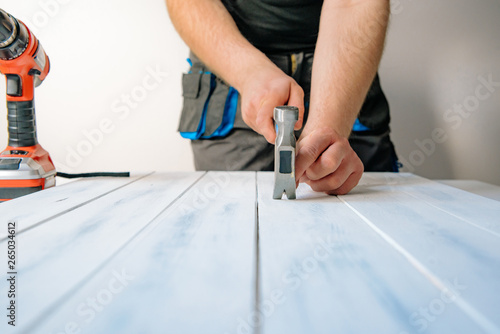 The man pulls out a nail from a wooden board. The concept of DIY and renovation of new things. A man tinkering at home, working with wood.