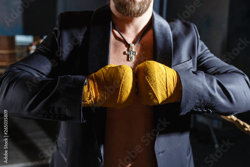 close-up of the hands of a boxer in bandages in a jacket on the naked body with a cross around his neck. portrait of fighters applying bondage tape on hands