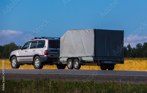 Car with a Trailer moves on a country road photo